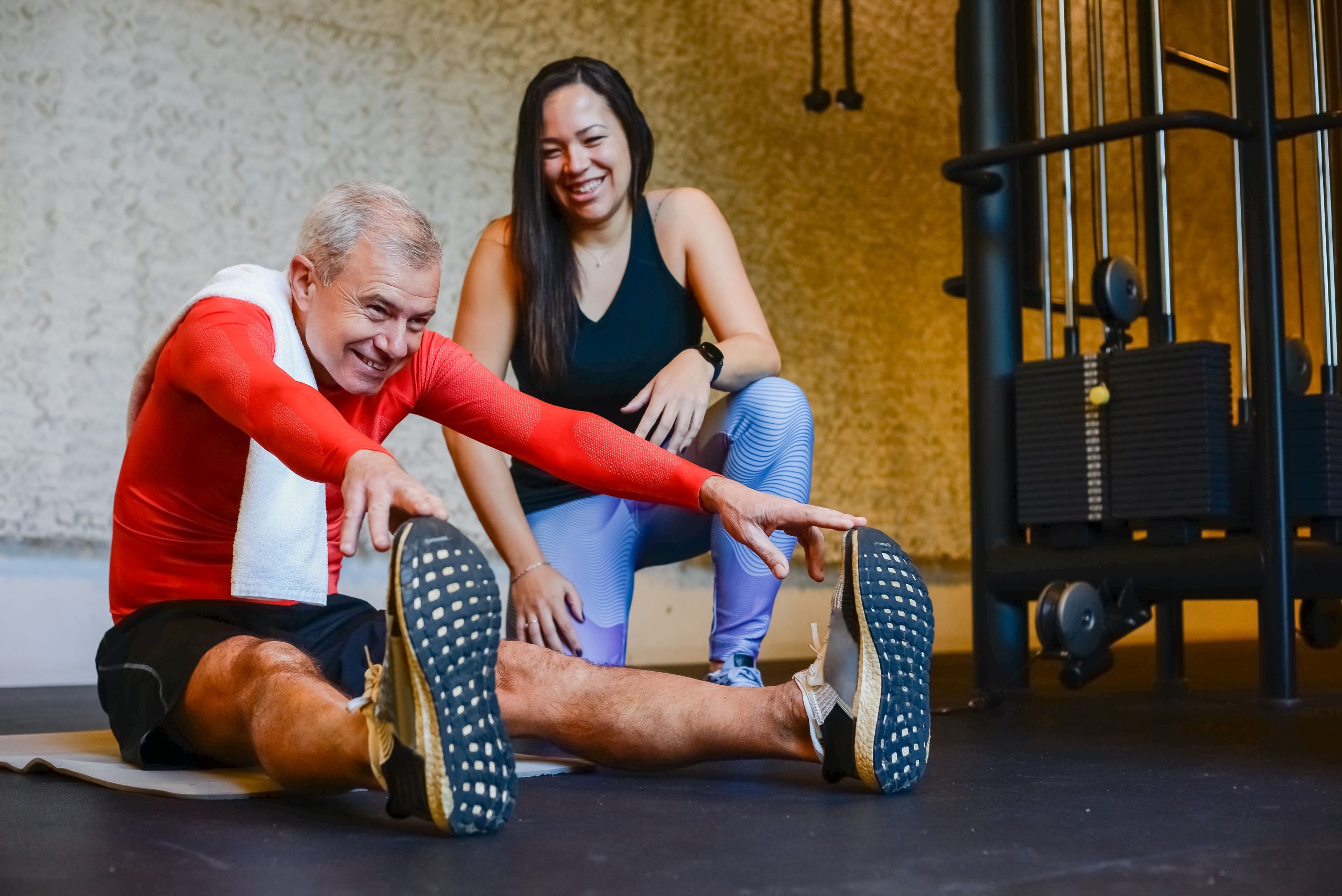 Homme âgé s'étirant avec coach en salle