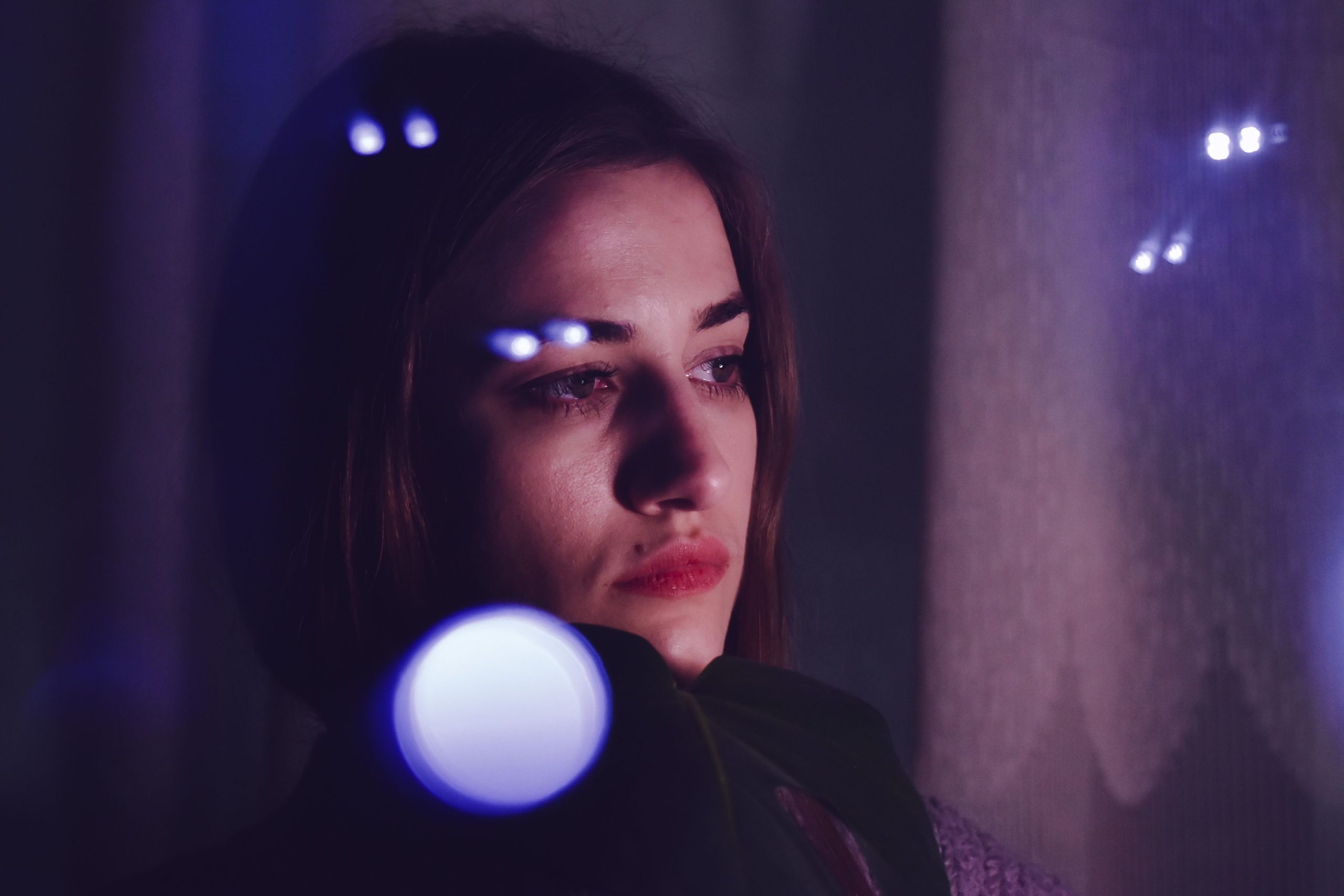 Femme bouleversée regardant par fenêtre dans l'obscurité