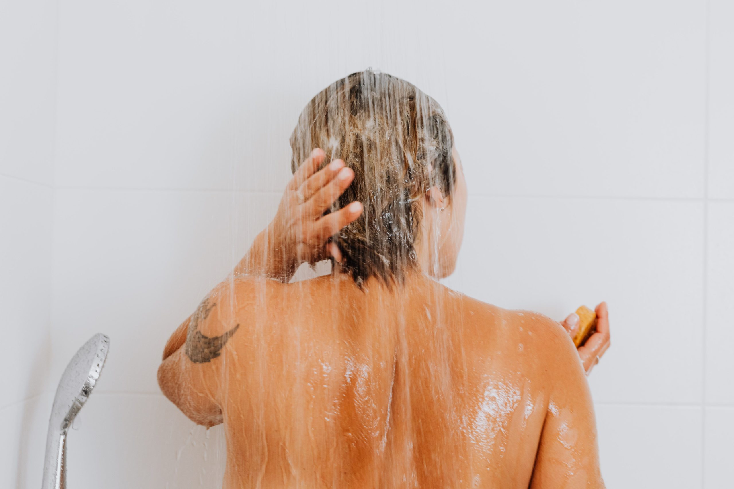 Femme rinçant ses cheveux sous douche