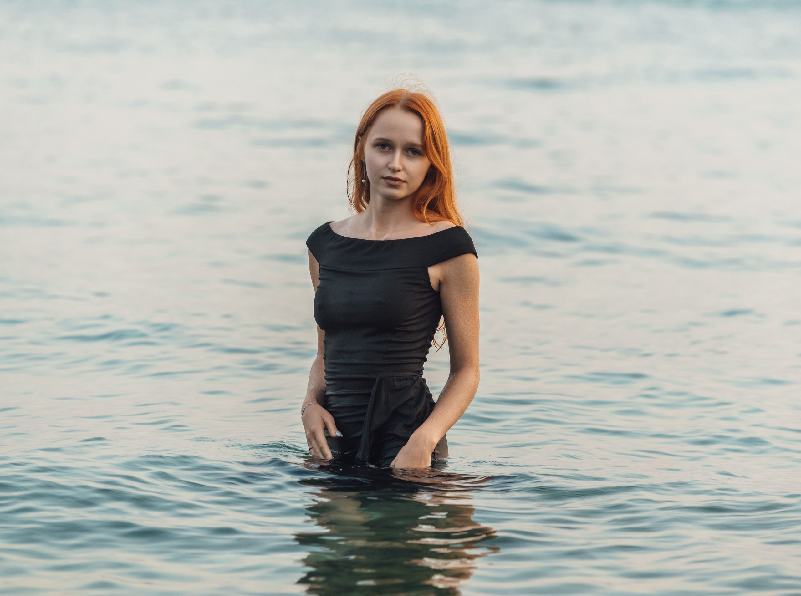 Femme en robe noire face à la mer