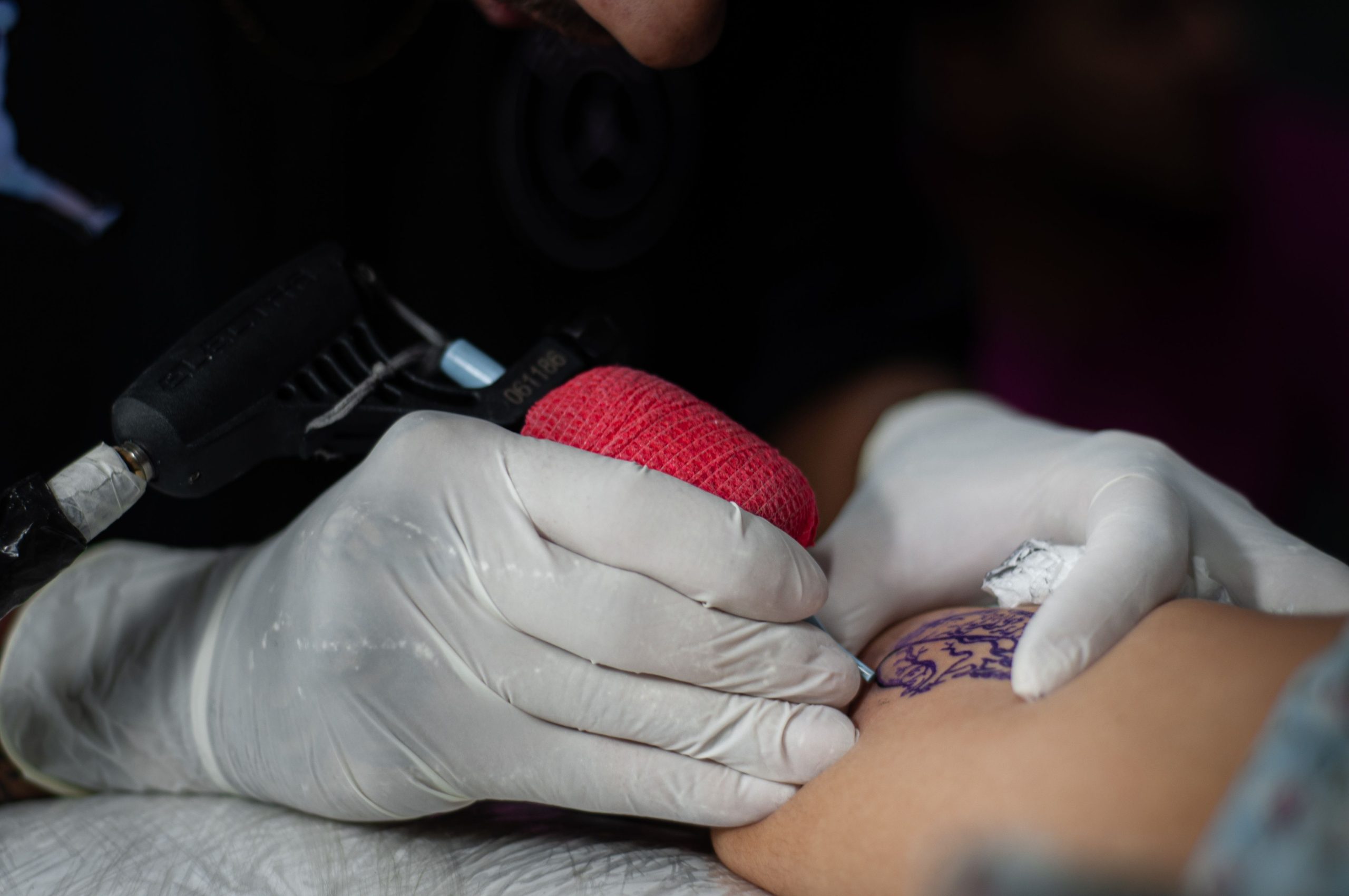 Tatoueur appliquant un blanc tattoo sur bras.
