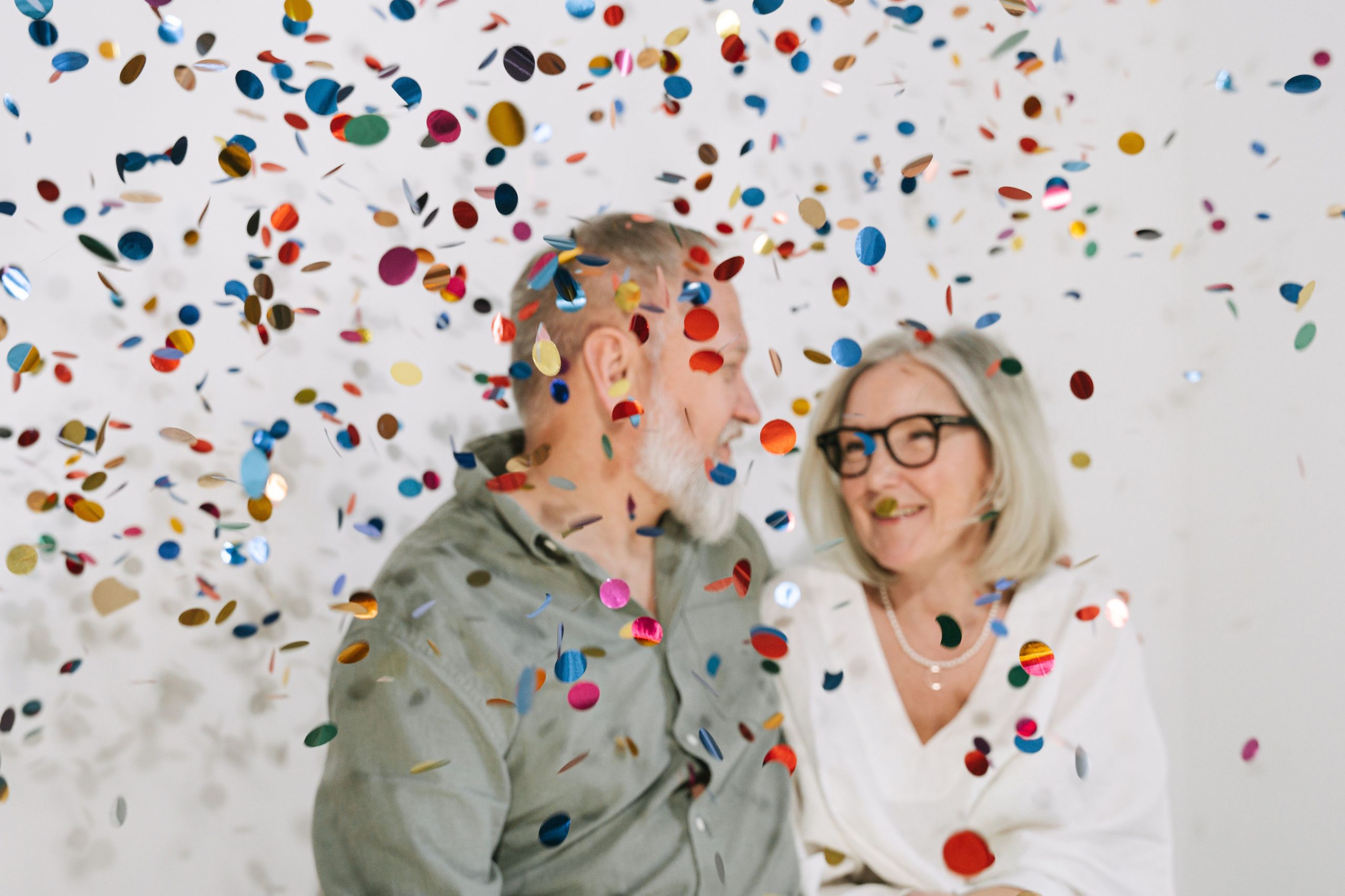 Couple senior fêtant avec confettis colorés à l'intérieur