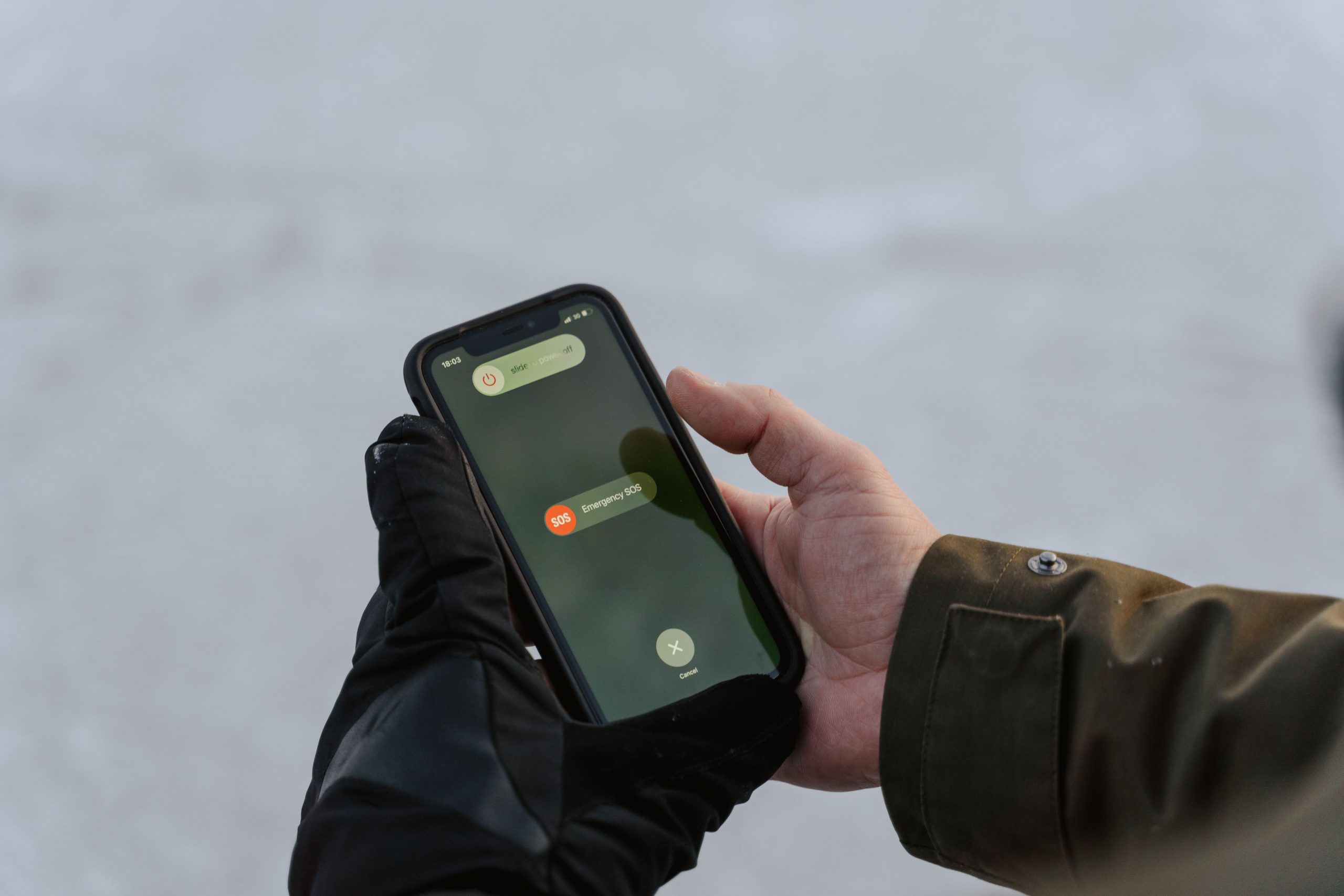 Mains gantées tenant un téléphone avec écran SOS
