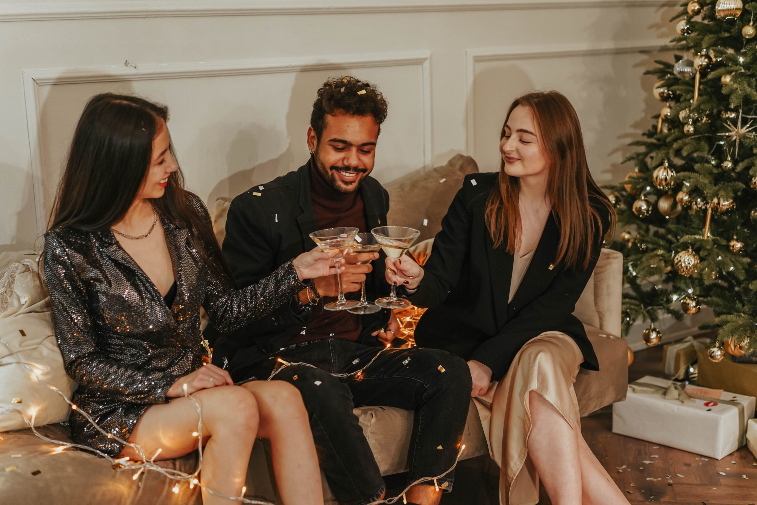 Trois amis célébrant le Nouvel An avec champagne sapin