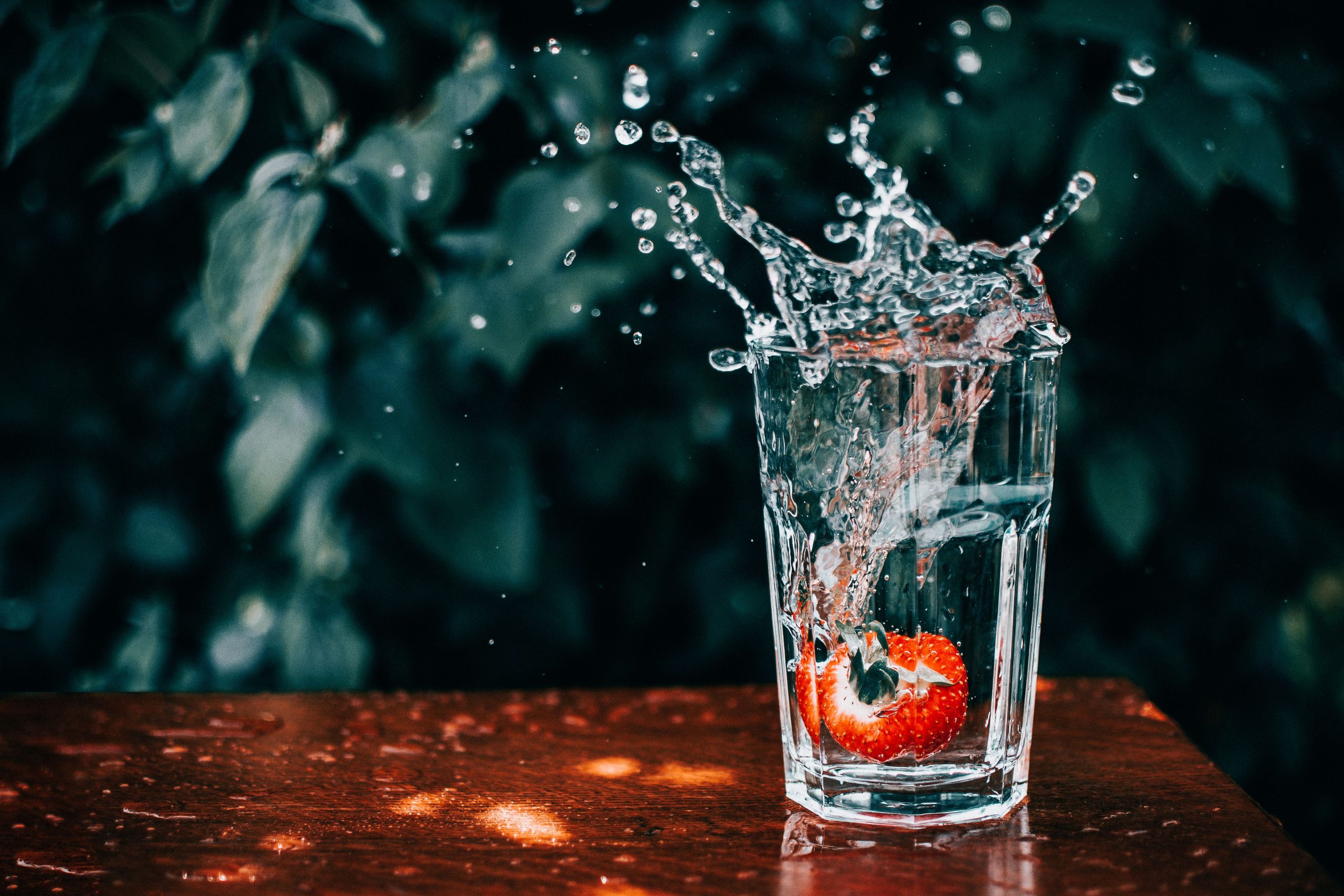 Fraise éclaboussant dans verre d'eau