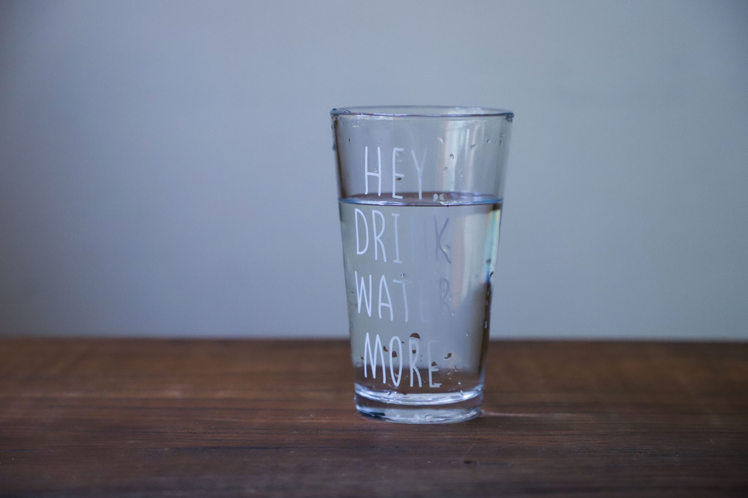 Verre d'eau sur table bois texte boire
