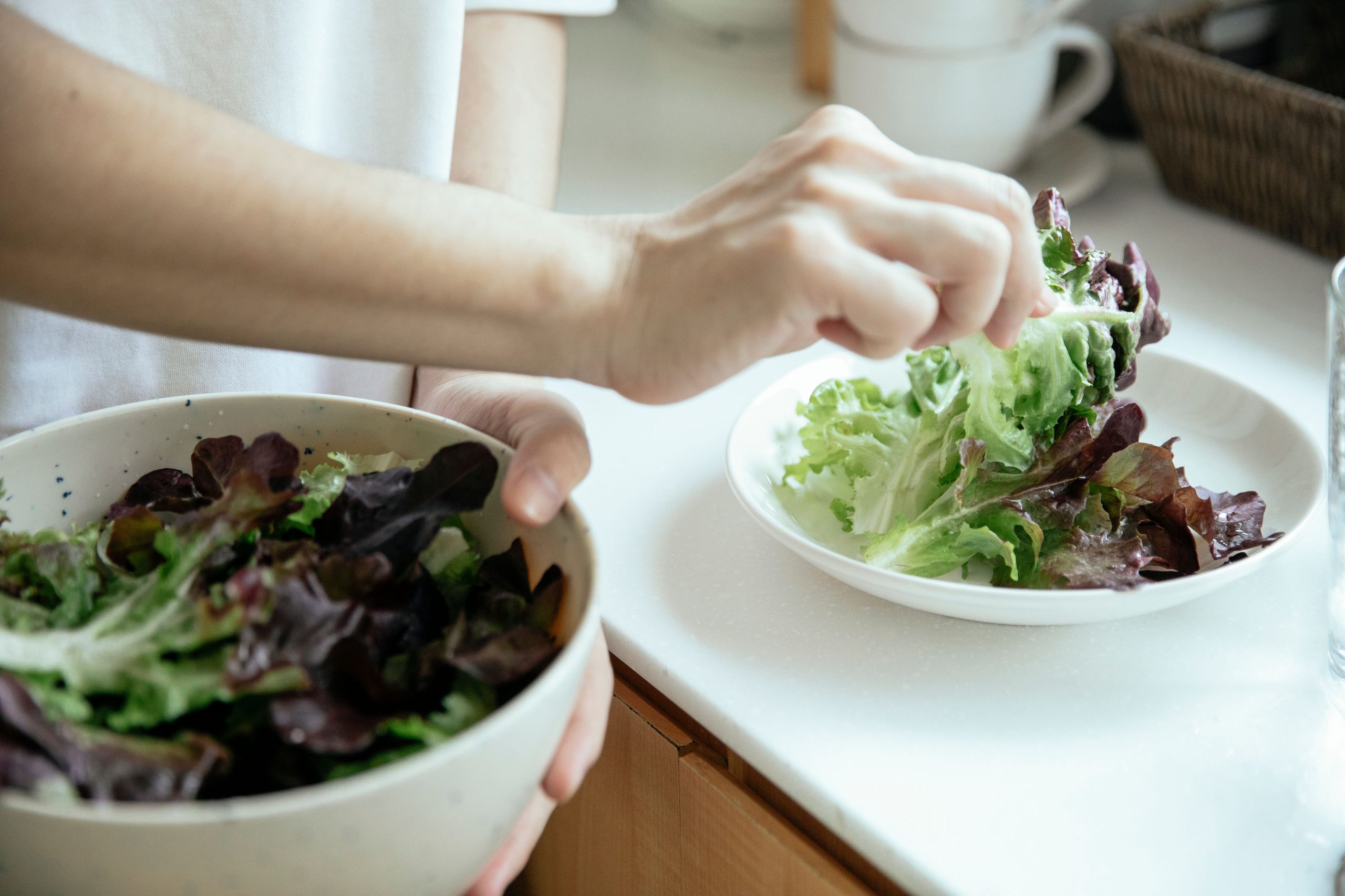 Personne versant de la salade dans une assiette