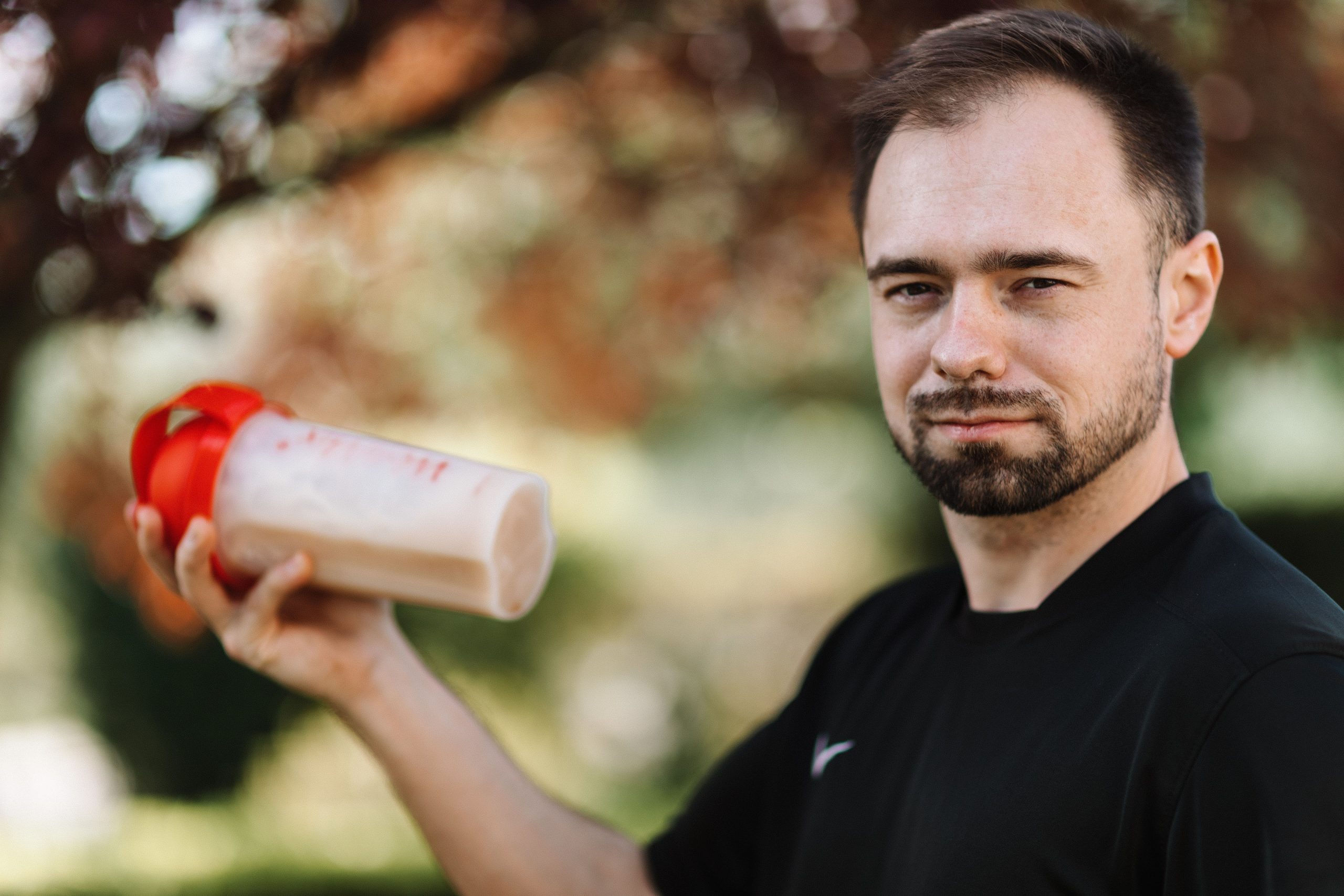 Homme tenant un shaker de protéine à l'extérieur