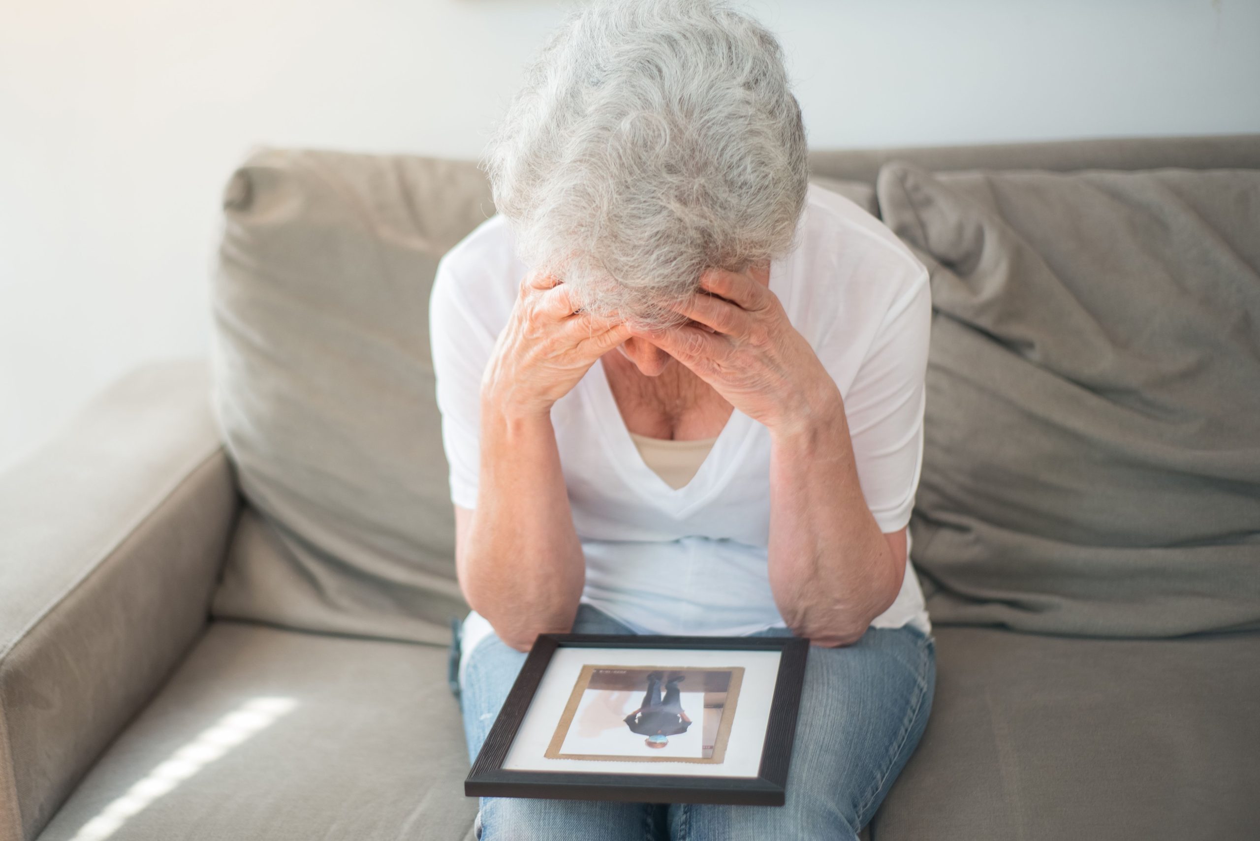 Femme âgée assise, tenant un cadre photo