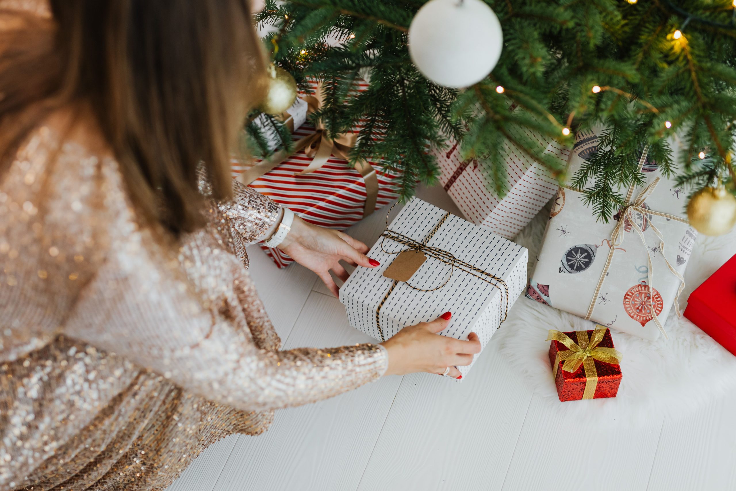 Femme plaçant cadeaux sous sapin orné
