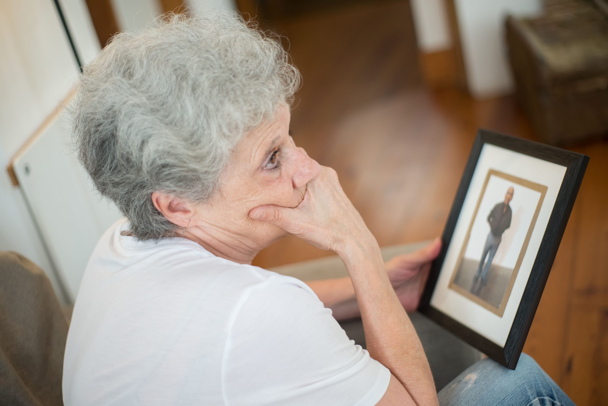 Femme âgée pensive avec une photo encadrée